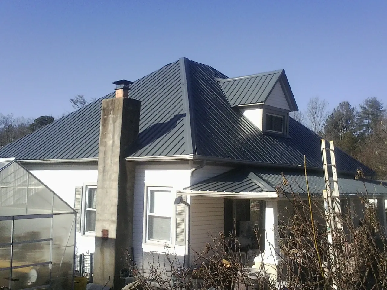 Dark blue standing seam metal roof on a white farmhouse with dormer — Slate & Tile Roof Repair by Roofing Brothers in Mount Prospect