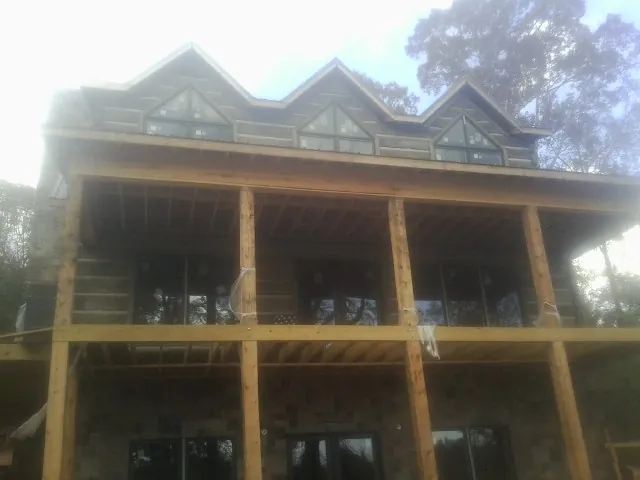 Dormers and porch framing on a large log home under construction — Roof Coating work by our crew in Mount Prospect