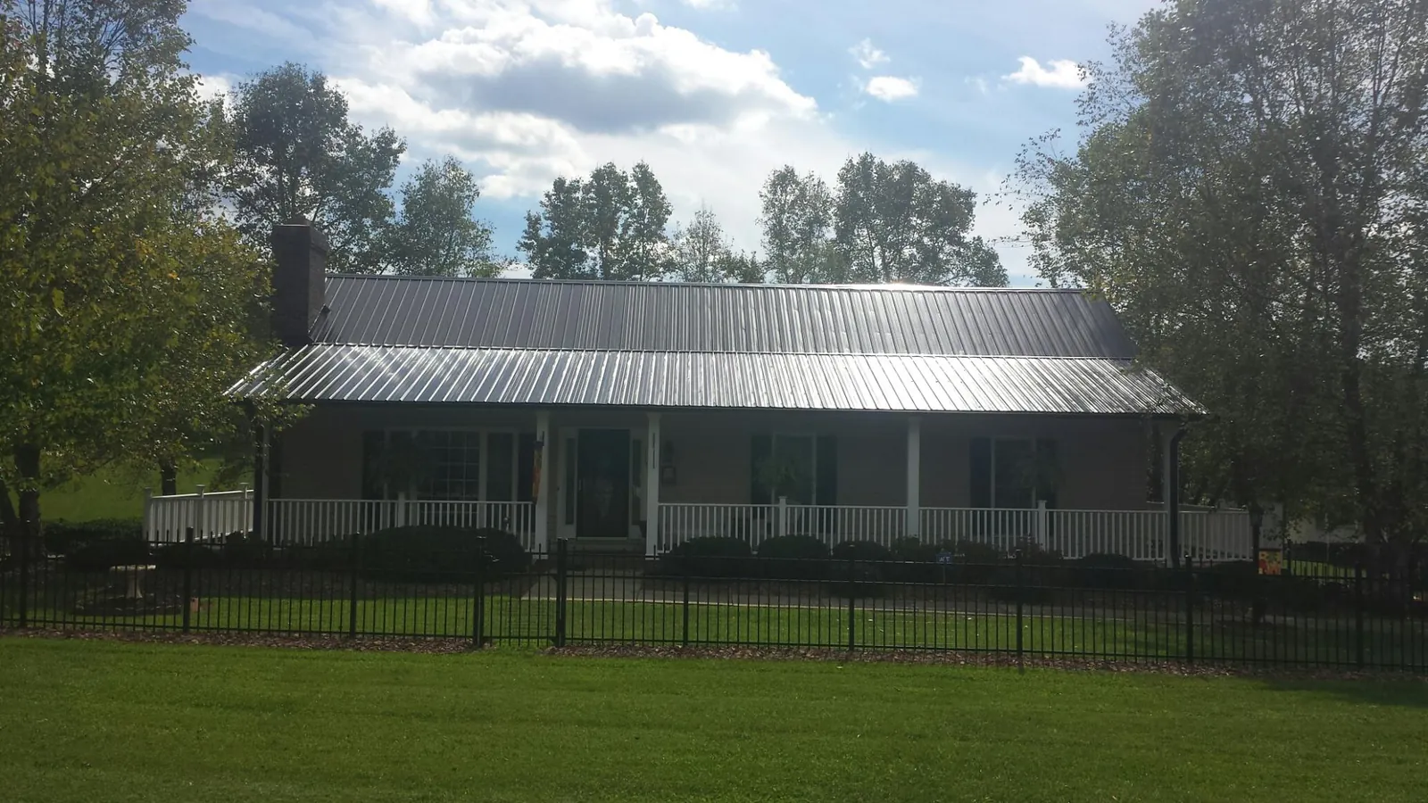 Gray metal roof on a brick ranch with a full width front porch — Gutter Guard Installation work by our crew in Mount Prospect