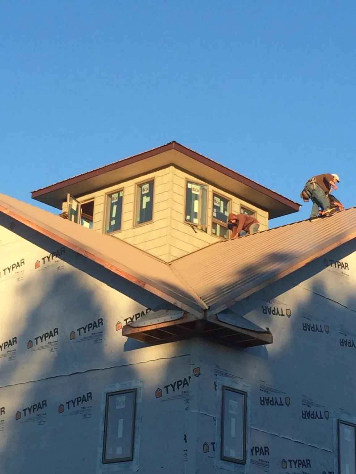 Roofers working around a rooftop cupola on a new metal roof at sunset — Roof Waterproofing in Mount Prospect by Roofing Brothers